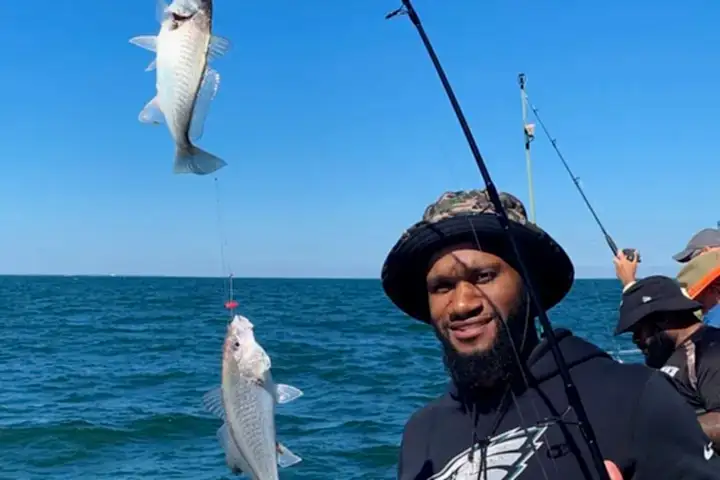 a man holding a fish on a boat in the water