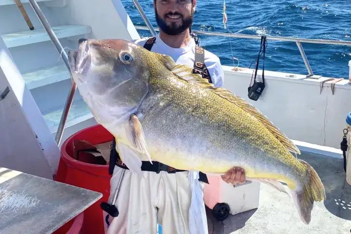 a man holding a fish on a boat in the water
