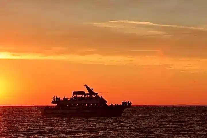 a large ship in a body of water with a sunset in the background